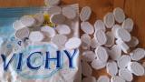 Un paquet de pastilles de Vichy ouvert sur une table en bois, des dizaines de pastilles blanches octogonales marquées Vichy ou 200 ans