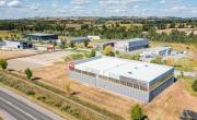 une vue aérienne montrant la zone des ancises avec la route en bas et un bâtiment au premier plan, marqué sur sa façade Meridia et Aluprod Auvergne. On distingue ensuite 8 autres bâtiments industriels en arrière plan.