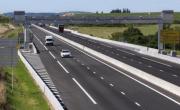 une autoroute à 4 voies avec le péage à flux libre comprenant un portique surplombant la route. Plusieurs véhicules roulent, un panneau indique péage flux libre A79