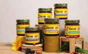 Des pots en verre avec des étiquettes Yacon & Co avec au premier plan des carrés de chocolat, noisette et une fleur de yacon