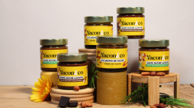 Des pots en verre avec des étiquettes Yacon & Co avec au premier plan des carrés de chocolat, noisette et une fleur de yacon