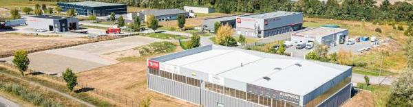 une vue aérienne montrant la zone des ancises avec la route en bas et un bâtiment au premier plan, marqué sur sa façade Meridia et Aluprod Auvergne. On distingue ensuite 8 autres bâtiments industriels en arrière plan.