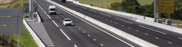 une autoroute à 4 voies avec le péage à flux libre comprenant un portique surplombant la route. Plusieurs véhicules roulent, un panneau indique péage flux libre A79
