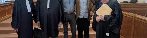 Les dirigeants des deux entreprises au milieu de 3 avocats et un représentant du personnel, dans une salle de tribunal