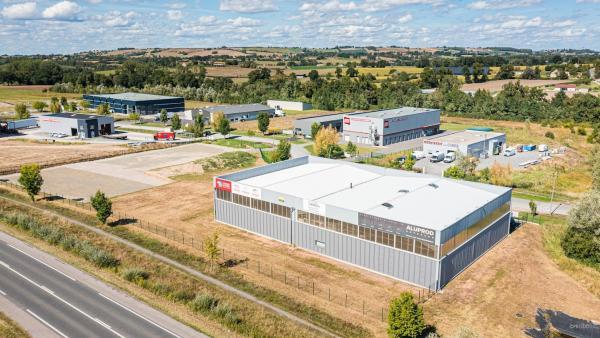 une vue aérienne montrant la zone des ancises avec la route en bas et un bâtiment au premier plan, marqué sur sa façade Meridia et Aluprod Auvergne. On distingue ensuite 8 autres bâtiments industriels en arrière plan.