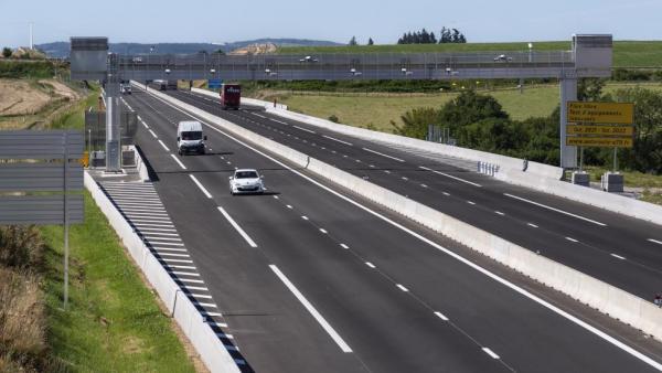 une autoroute à 4 voies avec le péage à flux libre comprenant un portique surplombant la route. Plusieurs véhicules roulent, un panneau indique péage flux libre A79