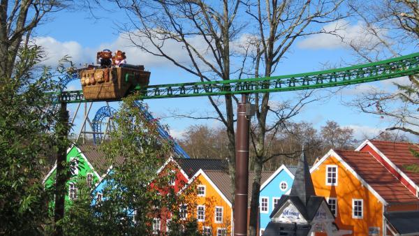 Une nacelle en forme de montgolfière sur un rail vert en hauteur accueille les deux mascottes du parc Le Pal et surplombent la zone du fjord explorer avec ses maisons scandinaves colorées.