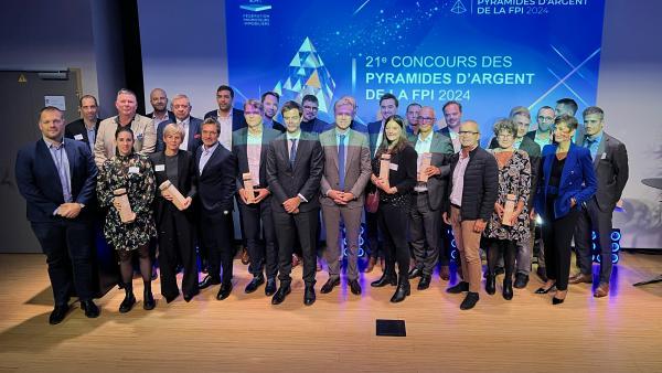 Au centre de la scène, Vincent Davy, président de la FPI Alpes et Bruno Converso, président de la Fédération Isère du BTP, entourés des lauréats et des partenaires des Pyramides d’Argent du sillon alpin.